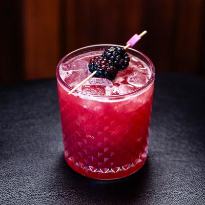 Red cocktail with blackberry garnish.