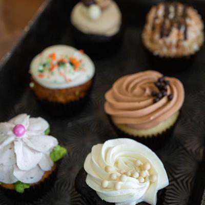 Assorted cupcakes on a black tray.
