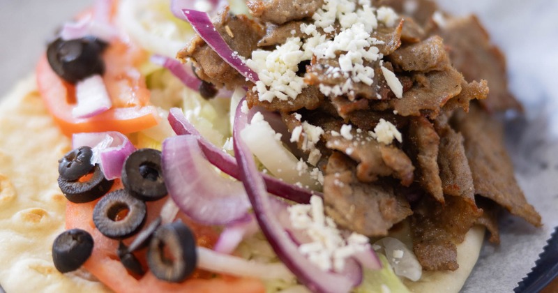 Lamb Gyro served over pita bread with black olives, tomato, onion and cheese