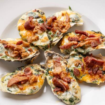 Oysters baked with a topping of finely chopped greens and bacon pieces.