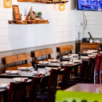 Restaurant interior, neatly arranged tables by a wall, set with tableware.
