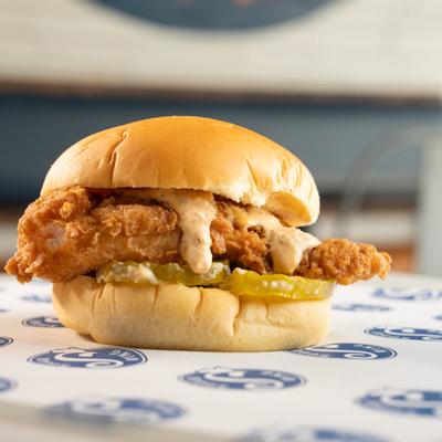 Fried chicken sandwich with pickles and sauce on a bun.