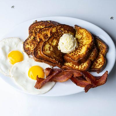 French toast served with bacon and two sunny-side-up eggs.