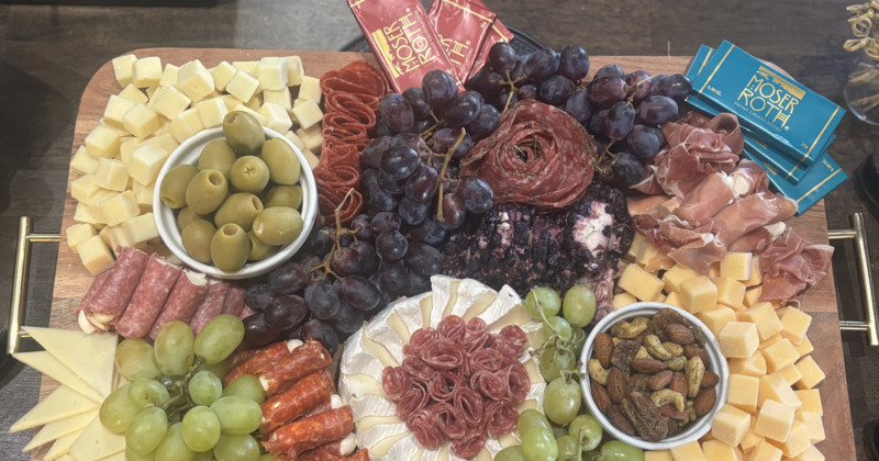 Charcuterie and cheese board filled with a variety of  meats, cheeses, fruits, and chocolates