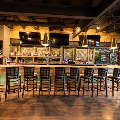 Interior, a bar with bar chairs and TV screens.