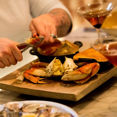 a person shelling a whole dungeness crab to enjoy for their meal