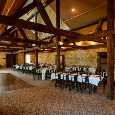 Interior with table seating, rustic exposed wood beams and limestone walls.