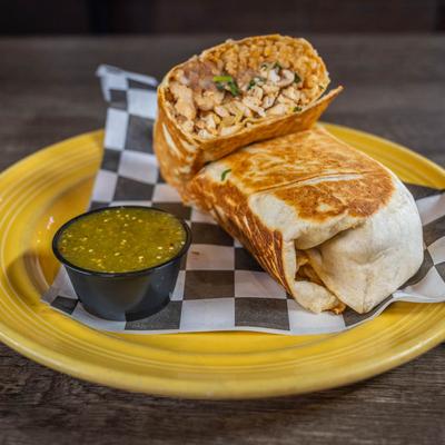 Chicken burrito served with green salsa on the side.