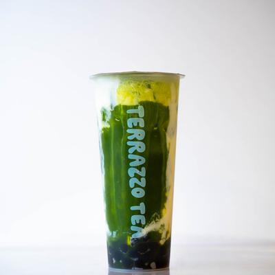Tall cup of bubble green tea with a layer of foam.