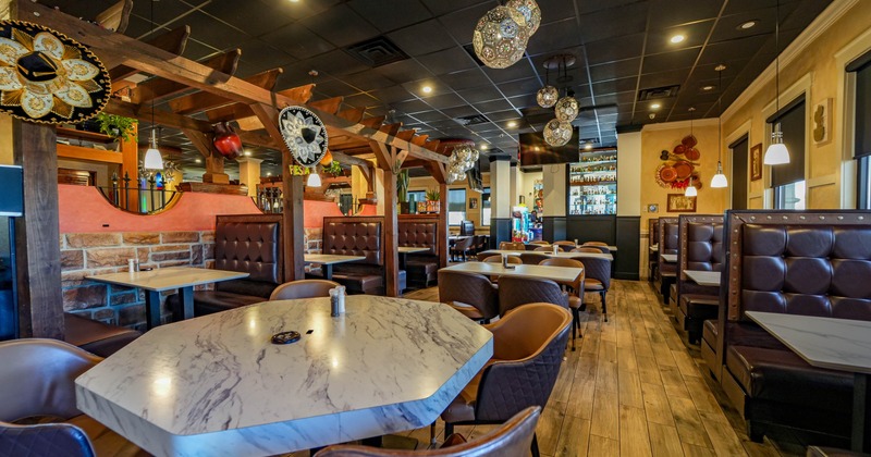 Interior of a restaurant with brown booths, marble tables, and festive decorations