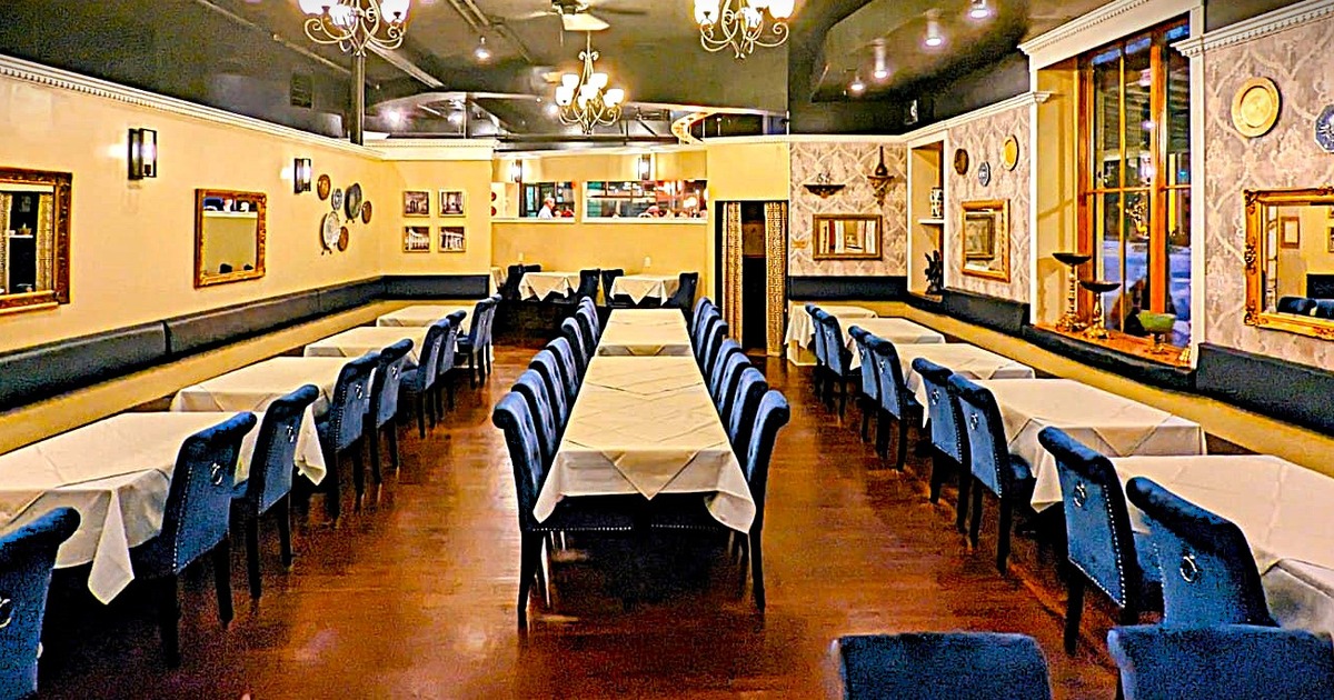 Elegant dining room with long tables covered in white tablecloths, surrounded by blue chairs