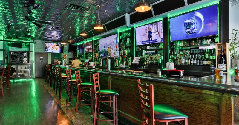Angle view to bar, stools, tv screens above drink rack