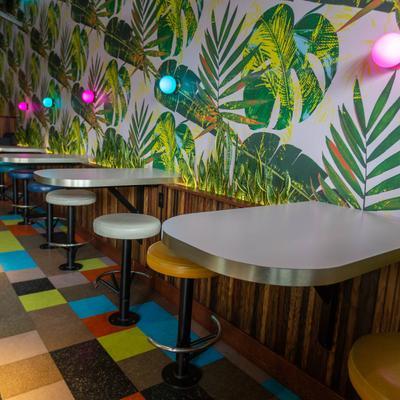Interior, builtin tables and bar stools, greenery wallpaper and color LED lights