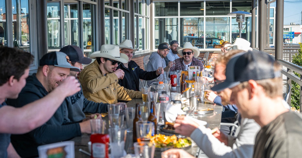 A group of people dining and enjoying drinks in an outdoor seating area