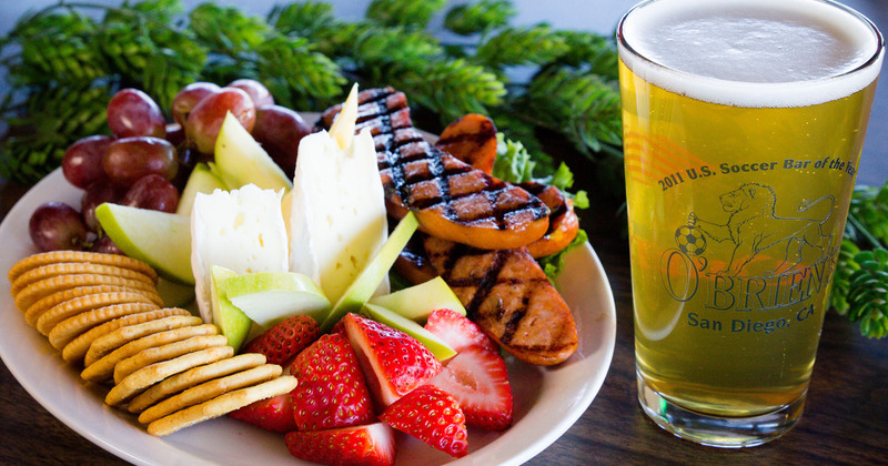Meat, strawberries, cheese and crackers plate and a glass of draft beer