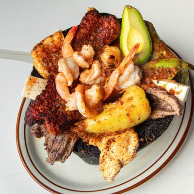 Molcajete meal served sizzling in a volcanic rock mortar, overhead view.