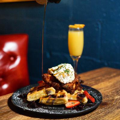 Served Chicken and waffles and a glass of Mimosa cocktail.