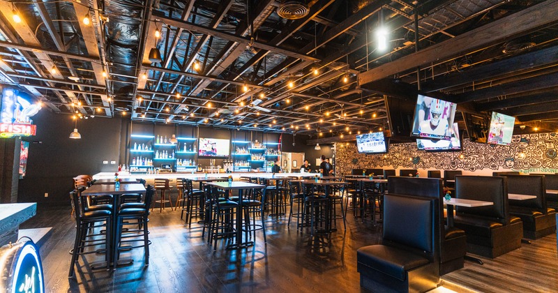 Tables with bar stools, restaurant booths, and a bar