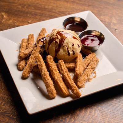 Churros served with ice cream and caramel sauce.