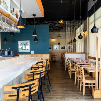 Interior of El Naranjo with bar seating and wooden dining tables.