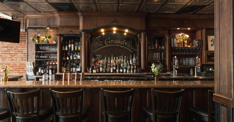 Interior, bar area, marble top bar with stool, large wooden drink shelves in the back