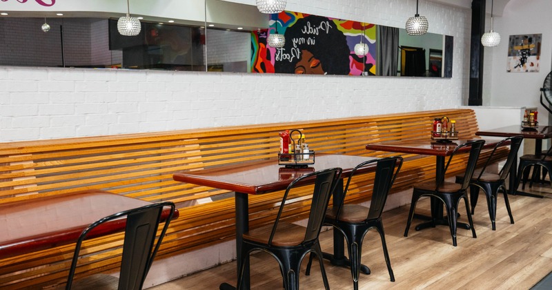 Interior, wooden tables, black metal chairs, pendant lights against white brick wall with mirrors