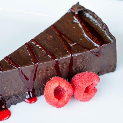 Flour-less Chocolate Cake garnished with fruit sauce drizzle and fresh raspberries