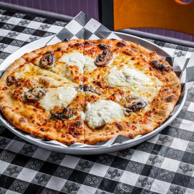 The Godmother Pizza featuring large dollops of ricotta cheese and roasted mushrooms.