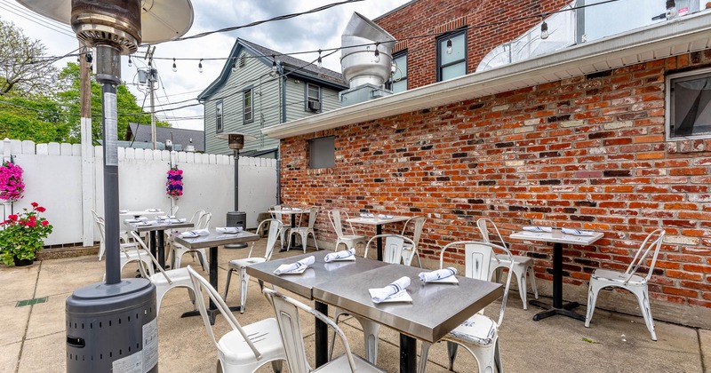 Exterior, seating area, inox top tables with metal chairs, space heaters, concrete flooring