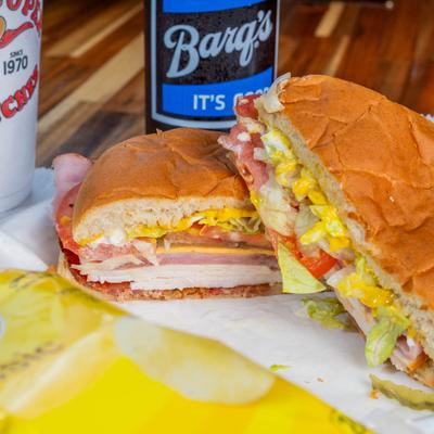 Sandwich with turkey, ham, lettuce, tomatoes, and cheese.