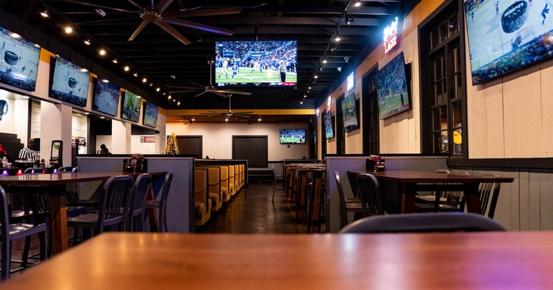 Interior, wide view of seating area, TV screens on the walls