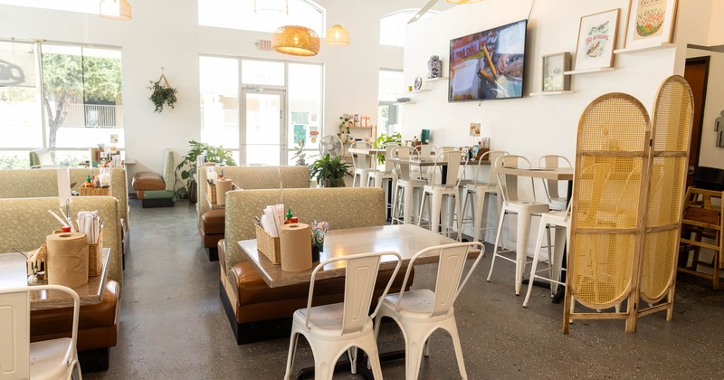 Bright, modern interior - booths, metal chairs, pendant lights, plants and decorative wall frames