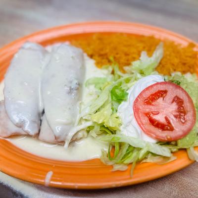 Enchiladas covered in a white cream, served with rice, sour creme and a salad.