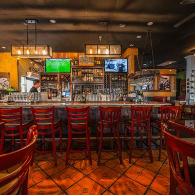 Interior, bar,stools, drink rack, tv screens above.