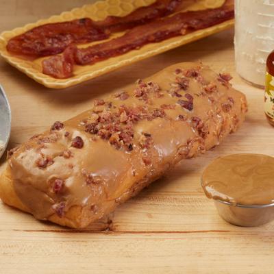 Maple bacon doughnut with glaze, crumbled bacon topping, and bacon on the side.