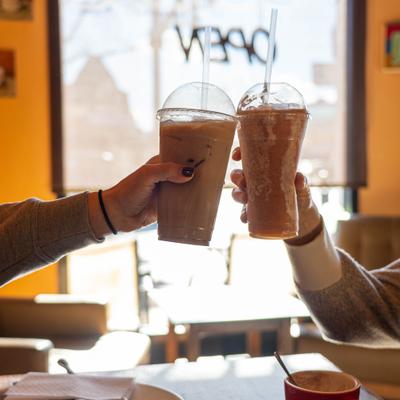 Two people raising their iced beverages in a toast.