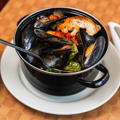 Mussels marinara in a black pot with toasted bread.