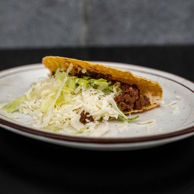 Hard shell taco served with seasoned ground beef and shredded lettuce.
