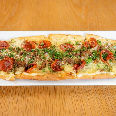 Flatbread with pesto, Alfredo sauce, pepperoni, Italian sausage, bacon, and Swiss.