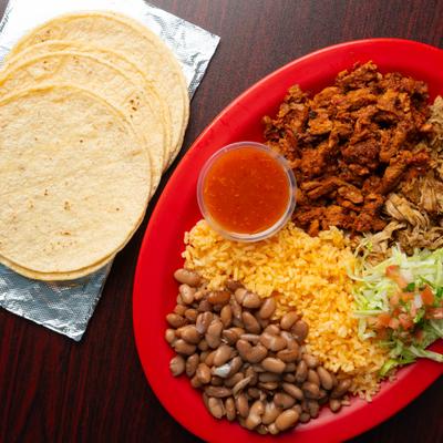 Mexican dinner platter with rice, pinto beans, seasoned meat, and salsa.