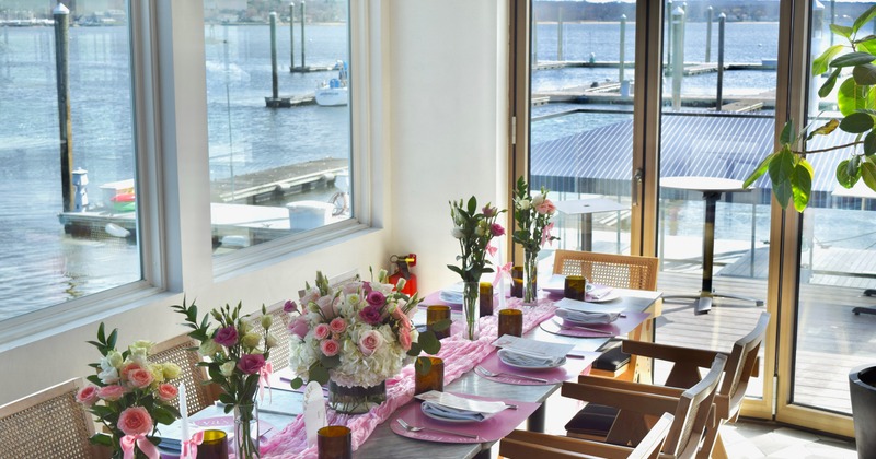 Elegant waterfront dining table decorated with pink flowers and place settings
