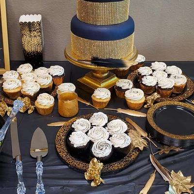 Elegant dessert table with a cake, cupcakes, gold decorations and cutlery.