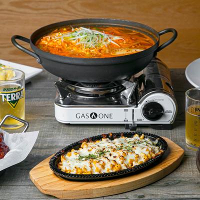 A steaming hot pot of ramen on a table with glasses of beer and plates of food.