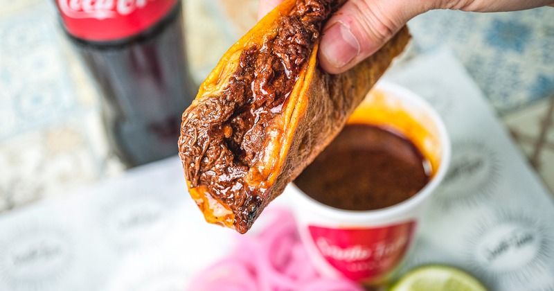 A close up view of a Birria taco in hand