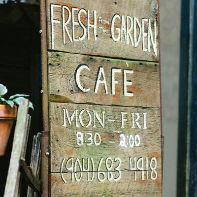 Rustic wooden sign featuring opening hours and a phone number.