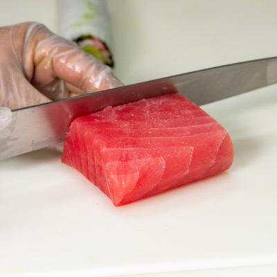 Fresh tuna being sliced on the cutting board.