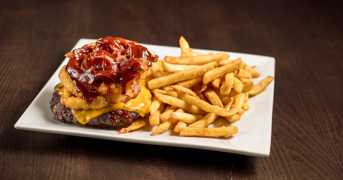 Bacon Cheeseburger topped with onion ring and served with fries