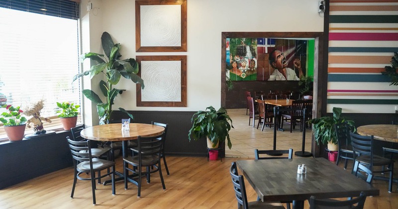 Interior, tables and chairs in two rooms with plants and decoration on the wall