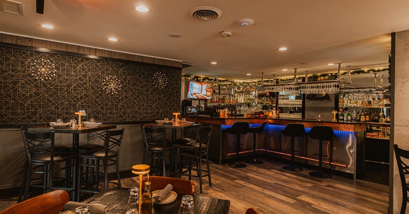 Interior, bar area, bar with stools, high seating tables for four, abstract wallpaper