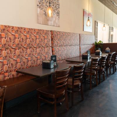 Dining area featuring patterned booth seating, wooden tables and chairs.